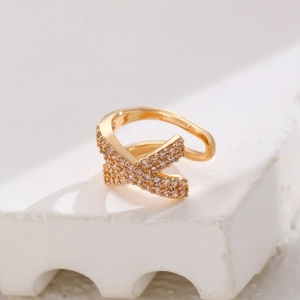 Macro shot of gold-plated X-cross ear cuff with micro-paved zircons on stone base