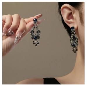 Detail of vintage silver earrings with deep blue gemstones and long tassel pendants