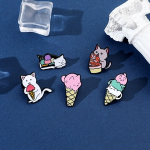 Detailed set of five cartoon cat and ice cream enamel pins on dark velvet background