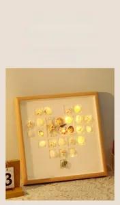 Detailed view of DIY shell heart picture frame with warm LED lighting on a lace tablecloth