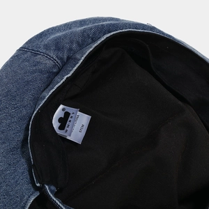 Detail of denim beret inner lining with care label and white size tag 57cm
