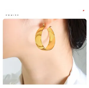Close-up of a wide polished 18K gold-plated U-shaped hoop earring worn by a model