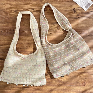 Detailed texture of knit crossbody tote featuring shell fringe and colorful glitter thread