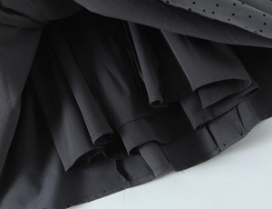 Detail of layered hemline with delicate polka dot flocking on dark fabric