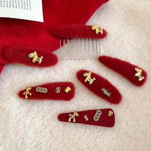 Detail of red plush hair clips set with golden pony charms on white fleece background