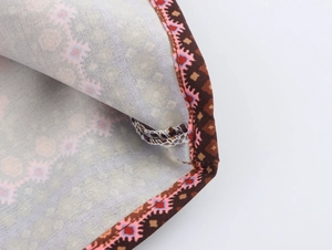 Gros plan détaillé du tissu à motif géométrique ethnique marron et coutures de mini robe