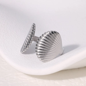 Macro shot of silver shell-shaped open ring with polished stainless steel texture