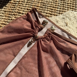Détail du maillot de bain en tulle marron foncé avec boucles métalliques dorées décoratives