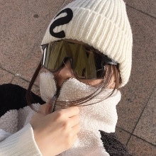 Close-up of golden reflective cycling goggles with white knit beanie and fleece jacket