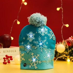Detail of teal knitted Christmas hat with white snowflake patterns and LED power switch