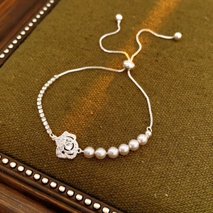 Détail du bracelet fleur avec chaîne argentée, perles blanches et oxydes de zirconium