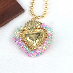 Macro detail of a colorful beaded necklace featuring an embossed gold heart pendant