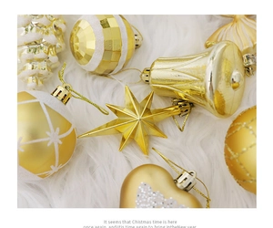 Flat lay of gold Christmas ornaments including stars and bells on a white faux fur rug