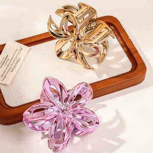 Close-up of gold and pink hollowed egg flower hair claws on a rustic wooden display tray