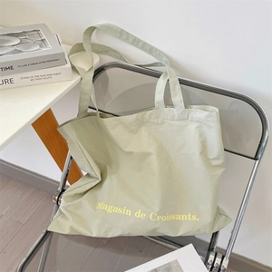 Primer plano del bolso tote de lona verde claro con texto amarillo en silla