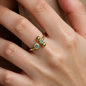 Detail of 18K gold plated X-shaped ring featuring blue and white zircon evil eye stones