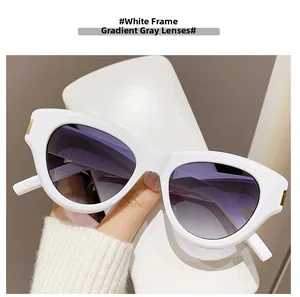 Detail of white cat eye sunglasses featuring gradient grey lenses and gold accents