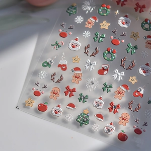 Macro shot of 3D Christmas nail art stickers featuring Santa and festive rhinestone details