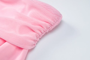 Detail of pink mesh fabric showing pleated cuffs and semi-transparent texture on a sleeve