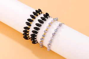 Detail of four beaded bracelets featuring black angular charms and lavender beads on a stand