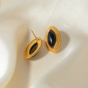 Macro detail of 18k gold stainless steel earrings with black onyx on silk fabric