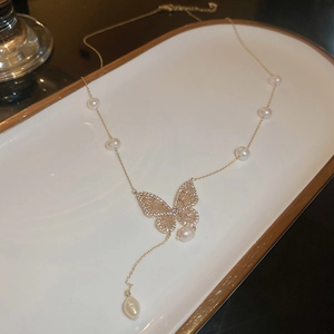 Detail of gold plated butterfly pendant necklace with freshwater pearls and zircons