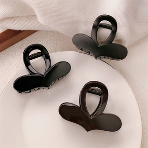 Three elegant black heart-shaped hair claw clips displayed on a white ceramic plate