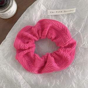 Detail of herringbone knit fabric on bright pink oversized scrunchie hair accessory