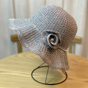 Detail of grey knitted sun hat with floral embellishment and pearl on wavy brim