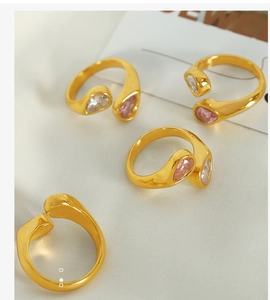Detail view of 18k gold plated stainless steel rings with pear-cut zircon on white fabric
