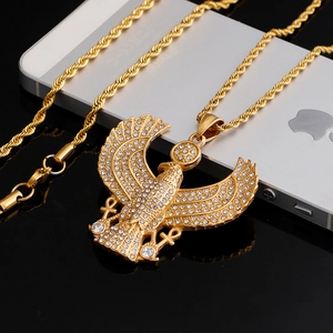 Macro shot of gold-plated Horus pendant with iced-out crystals and Ankh cross on black base