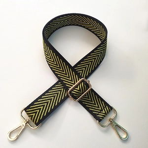 Detail of wide black shoulder strap with yellow chevron pattern and gold metal hardware