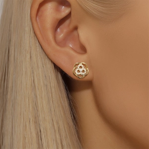 Close-up of golden petal-shaped stud earrings with sparkling zircon inlay on the ear