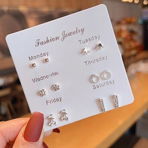 Close-up of 6 pairs of silver earrings with stars and floral designs on a display card