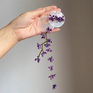 Détail de boucles d'oreilles papillon vintage avec disques de nacre et glands violets