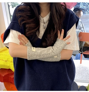 Macro shot of grey knitted fingerless arm sleeves featuring a small comment woven label