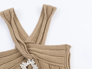 Close-up of camel knit top featuring a twisted neckline and sparkling crystal brooch