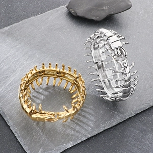 Detailed macro view of gold and silver centipede cuff bracelets on a stone background