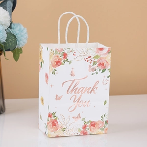 Close-up of white paper gift bag with floral prints and golden Thank You text