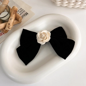 Détail d'un nœud en velours noir avec camélia blanc posé sur un plateau blanc
