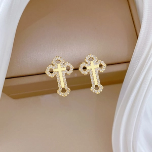 Elegant gold hollow cross earrings with sparkling zircon on beige jewelry box