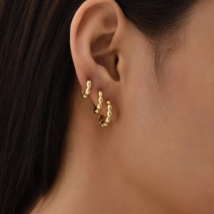 Detailed close-up of a three-piece gold bead textured hoop earring set on ear