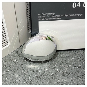 Detailed view of silver oval acrylic clutch with reflective mirror finish and chain strap