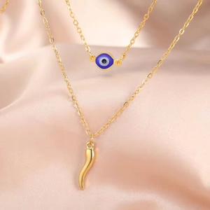 Detail of gold evil eye and Italian horn charms on double layered stainless steel chains