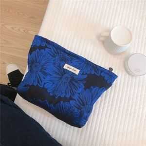 Macro detail of blue daisy jacquard fabric on travel makeup bag with zip closure