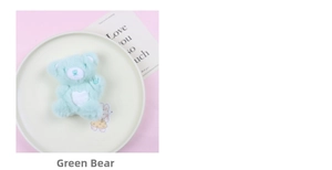 Detail of mint green plush bear charm with white heart on a decorative tray