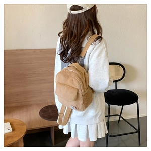 Mini mochila de felpa marrón con etiqueta Good Luck usada por una modelo en escena