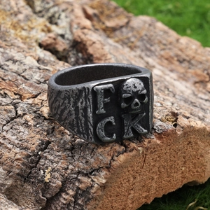 Punk style skull ring with FCK letters in vintage silver finish on bark background