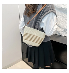 Detail of cream woven tote bag with brown stripes and adjustable leather strap