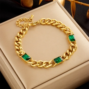 Macro detail of gold layered chain bracelet with three rectangular green gemstones